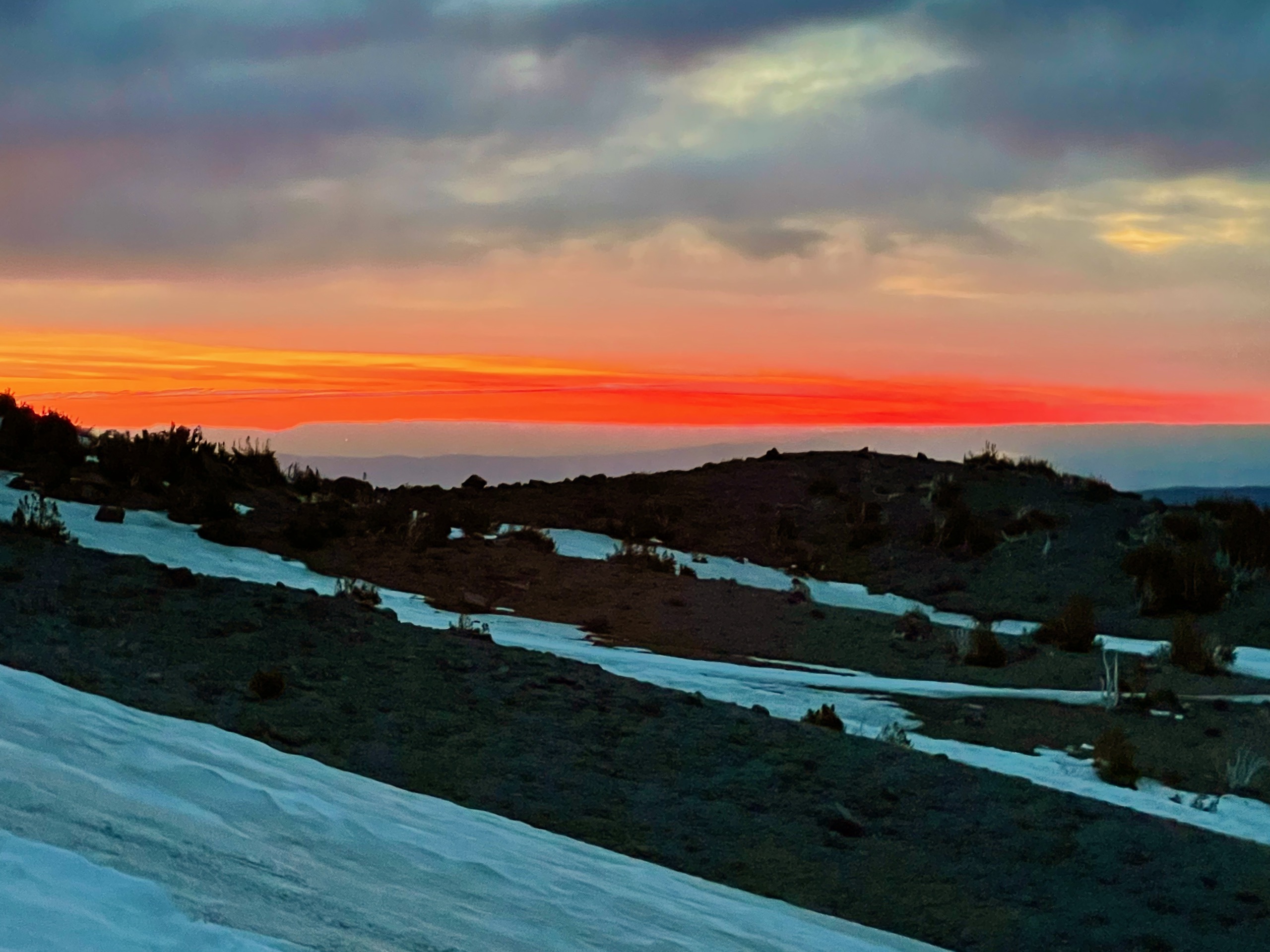 Sunrise over the eastern Oregon foothills. Patchy snow fields cover the volcanic shoulders in the foreground.